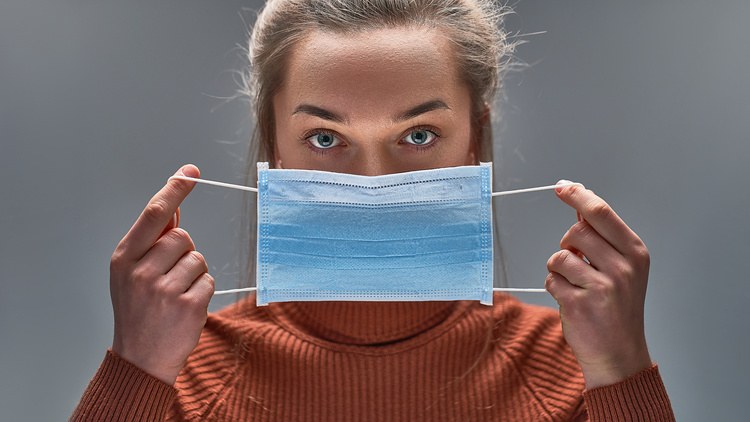 Rúško si nasadzujte tak, aby ste sa dotýkali iba gumičiek. Inak ho môžete infikovať koronavírusom. FOTO: Adobe Stock